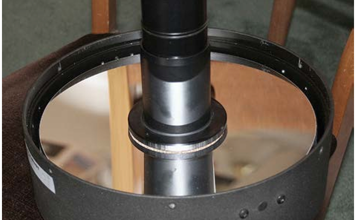 The primary mirror is face-up, with the secondary mirror unit at its centre. Both are exposed; the front corrector plate has been removed