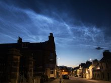 Noctilucent cloud over Thurso in Scotland, with silhouetted house in foreground