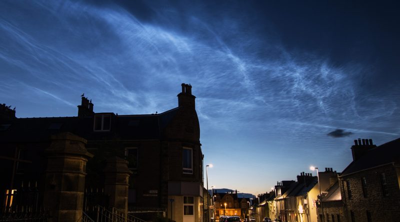 Noctilucent cloud over Thurso in Scotland, with silhouetted house in foreground