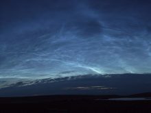 Rippling clouds of electric blue set against a dark northern sky, tinged with light as if twilight.